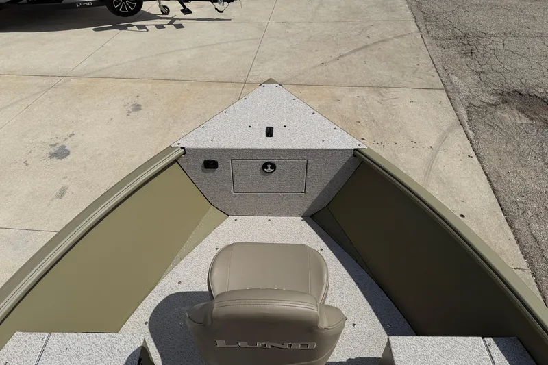 Slide: The Image of 2025 Lund 1875 Alaskan SS boat interior with seating and storage, parked on concrete. - 11