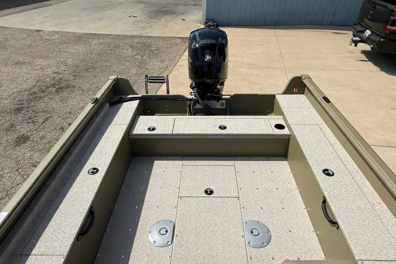 Slide: The Image of 2025 Lund 1875 Alaskan SS boat interior with motor, parked on concrete surface. - 28