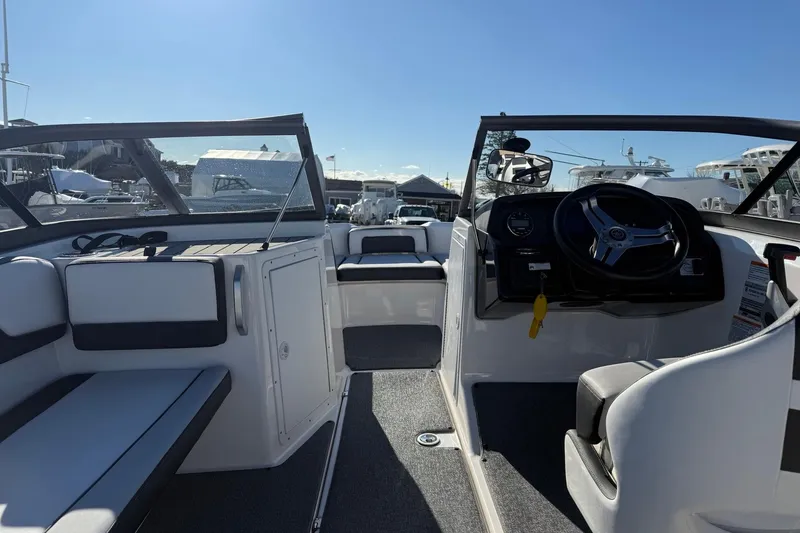 Slide: The Image of 2019 Yamaha Boats AR195 interior with steering wheel and seating, docked under clear sky. - 12