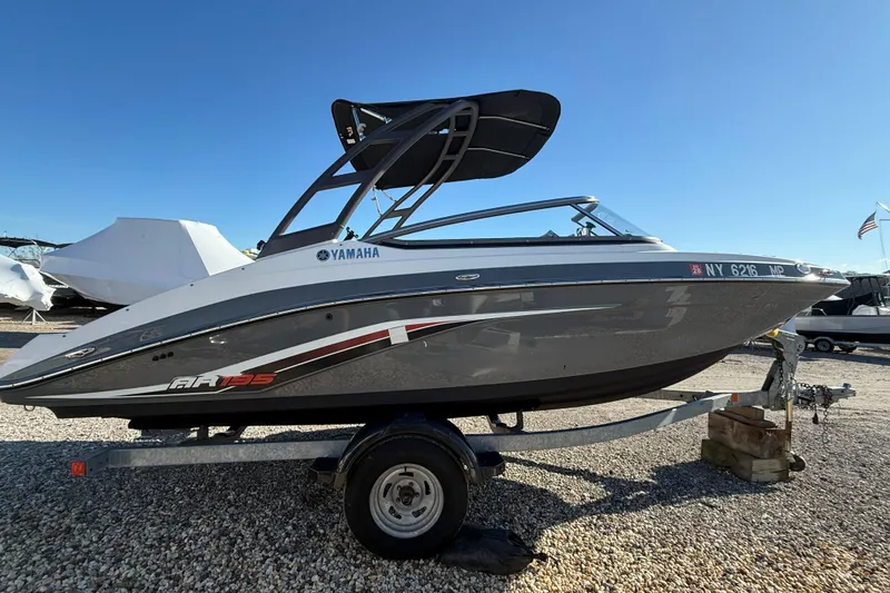 Slide: The Image of 2019 Yamaha Boats AR195 on trailer, sleek design, parked outdoors under clear blue sky. - 2