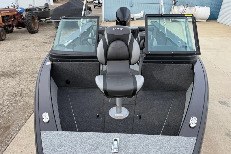 Slide: The Image of 2026 Lund 2075 Fisherman boat interior with seating and windshield, parked outdoors. - 9
