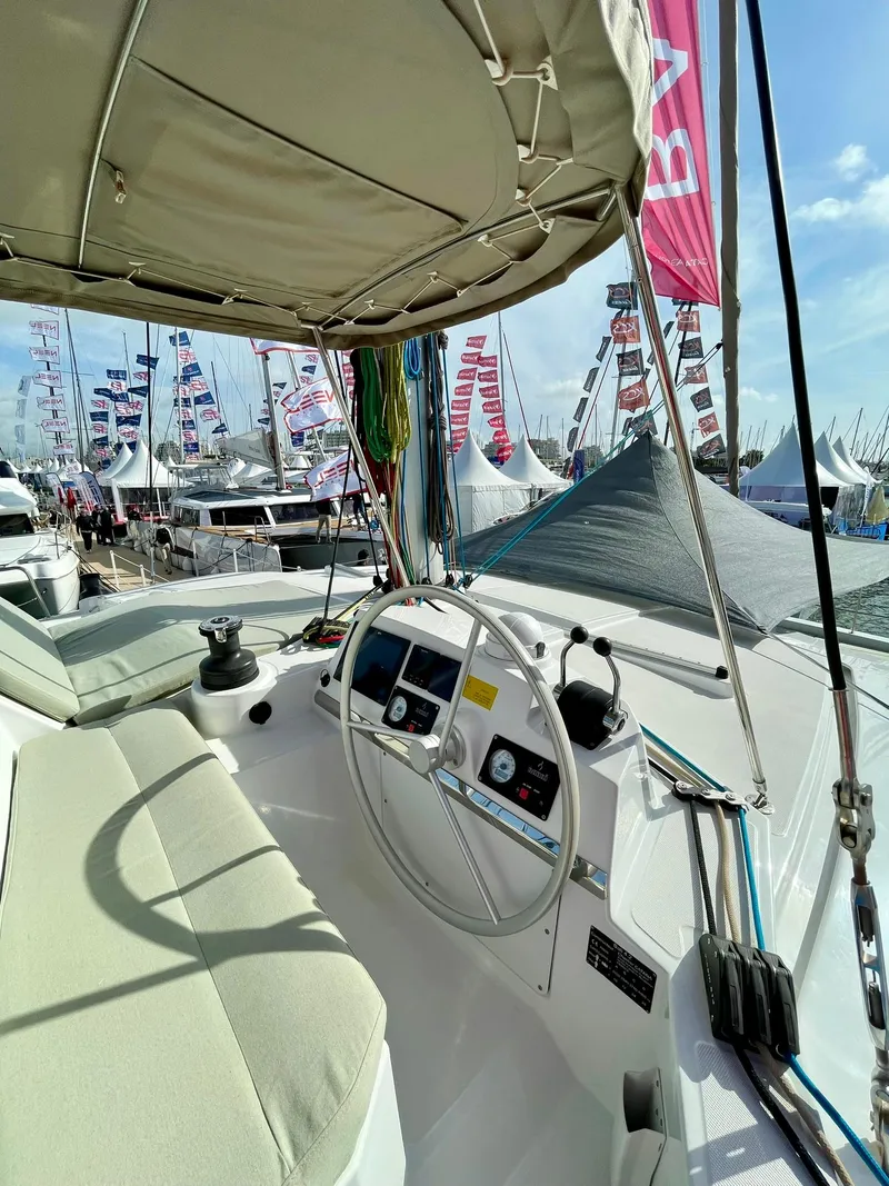 Slide: The Image of Steering area of 2026 Bali 4.2 yacht at a boat show, surrounded by flags and tents. - 8