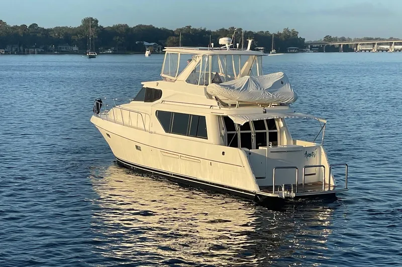 Slide: The Image of 1999 McKinna 57 Pilothouse yacht on calm water, with scenic background. - 2