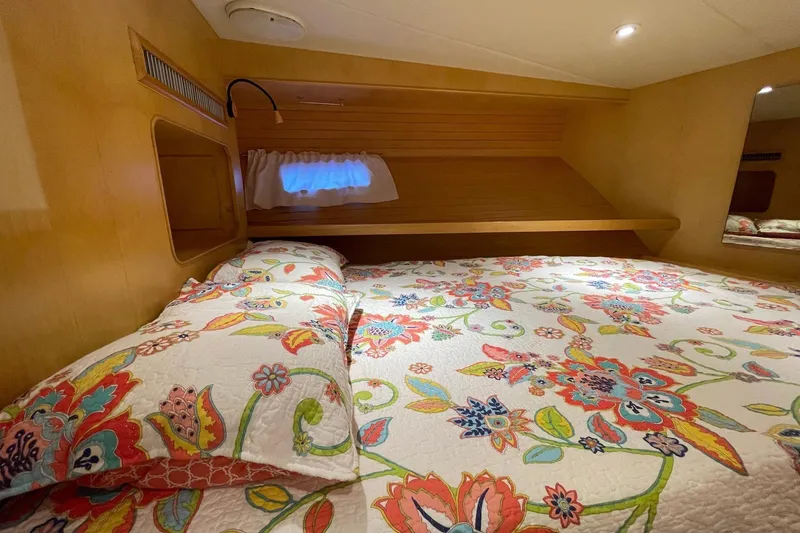 Slide: The Image of Floral bedding in 1999 McKinna 57 Pilothouse cabin, featuring vibrant colors and wooden accents. - 52