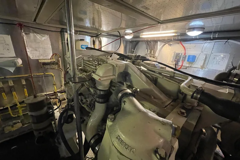 Slide: The Image of Engine room of a 1999 McKinna 57 Pilothouse yacht, showcasing mechanical components and wiring. - 60