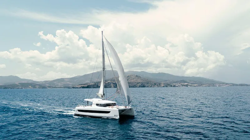 Slide: The Image of Sailing catamaran Bali CATSMART 2026 on open sea with scenic mountain backdrop. - 6