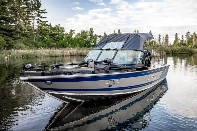 Slide: The Image of Manufacturer Provided Image: 2025 Lund 1875 Pro-V boat on a serene lake with lush greenery. - 3