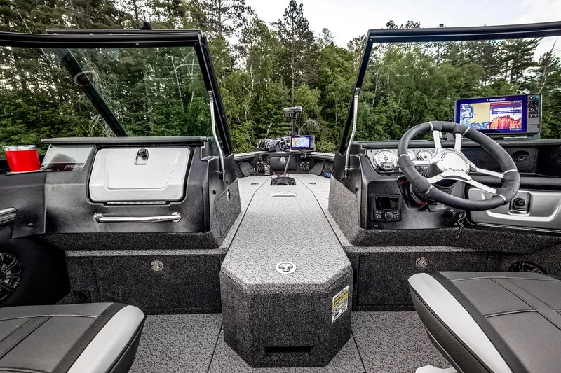 Slide: The Image of Manufacturer Provided Image: 2025 Lund 1875 Pro-V boat interior with modern dashboard and steering, surrounded by lush greenery. - 6