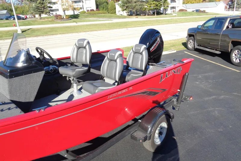 Slide: The Image of 2022 Lund 1650 Rebel XL SS boat with Mercury engine, parked beside a truck. - 2