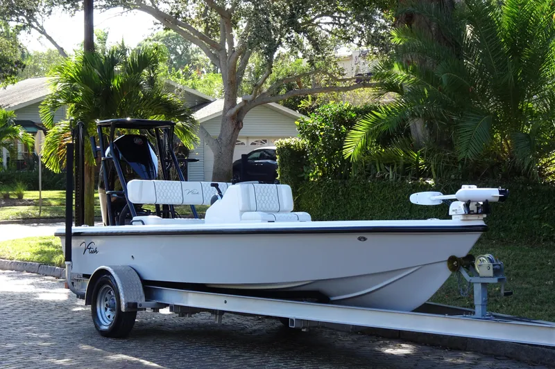 Slide: The Image of 2023 Vtech 18 boat on trailer, parked in a lush residential area. - 5