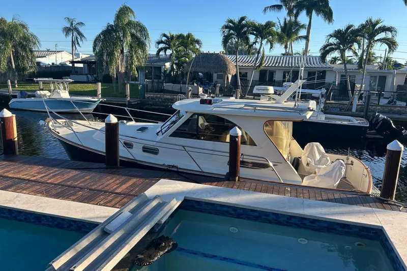 Slide: The Image of 2007 Legacy Yachts 32 Express docked by a canal with palm trees. - 2