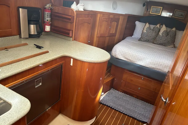 Slide: The Image of Cozy interior of 2007 Legacy Yachts 32 Express with bed, kitchenette, and wooden cabinetry. - 6