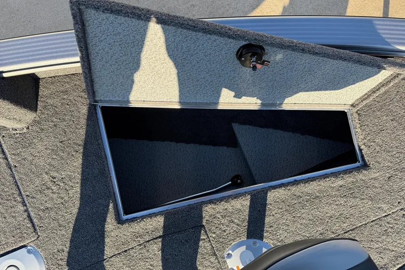 Slide: The Image of Open storage compartment on 2026 Lund 1875 Pro Guide boat, featuring carpeted interior. - 14