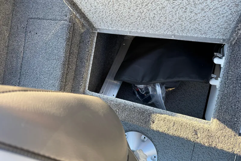 Slide: The Image of 2026 Lund 1875 Pro Guide boat storage compartment with gray carpet interior. - 22