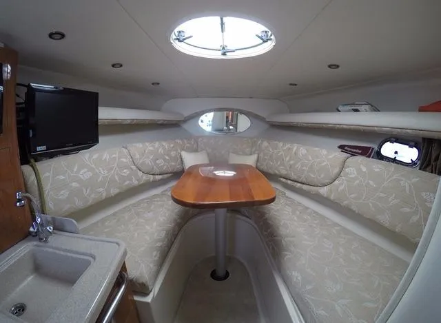 Slide: The Image of 2005 Four Winns 268 Vista cabin interior with seating, table, and porthole. - 21