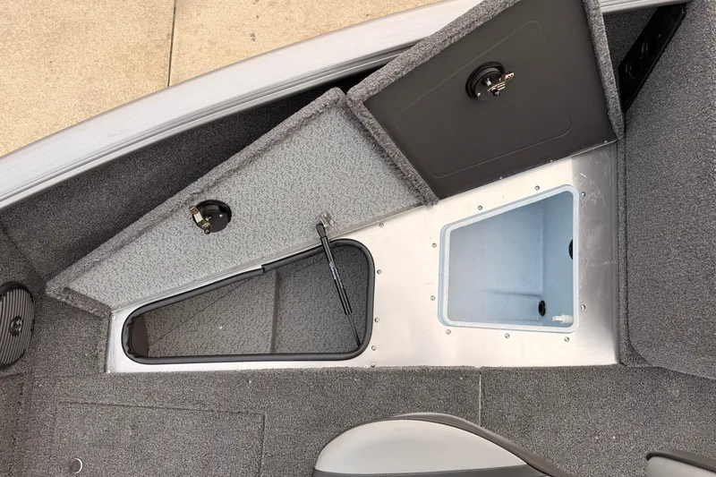 Slide: The Image of 2026 Lund 1775 Impact XS SS boat interior with storage compartments and carpeted flooring. - 14