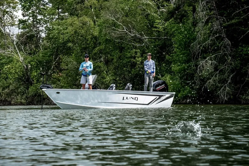 Slide: The Image of 2026 Lund 1775 Impact XS SS boat on trailer, parked near garages. - 2