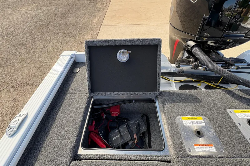 Slide: The Image of 2026 Lund 1875 Pro-V Bass XS boat battery compartment with charger and motor details. - 30