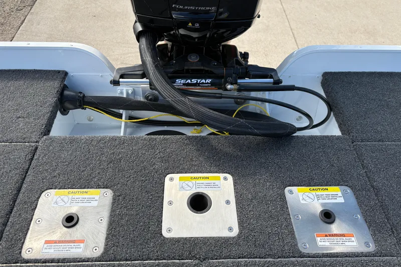 Slide: The Image of 2026 Lund 1875 Pro-V Bass XS boat deck with motor and caution labels. - 32