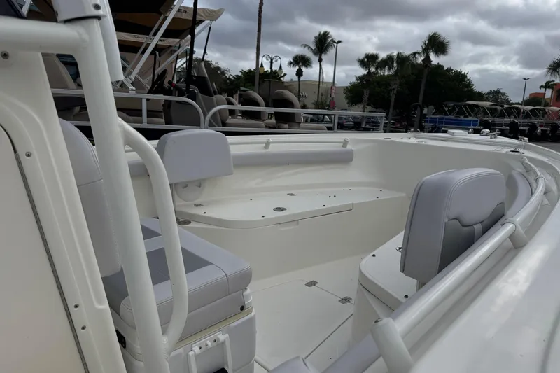 Slide: The Image of 2024 Mako 214 Center Console boat interior with seating and railings, under cloudy sky. - 5