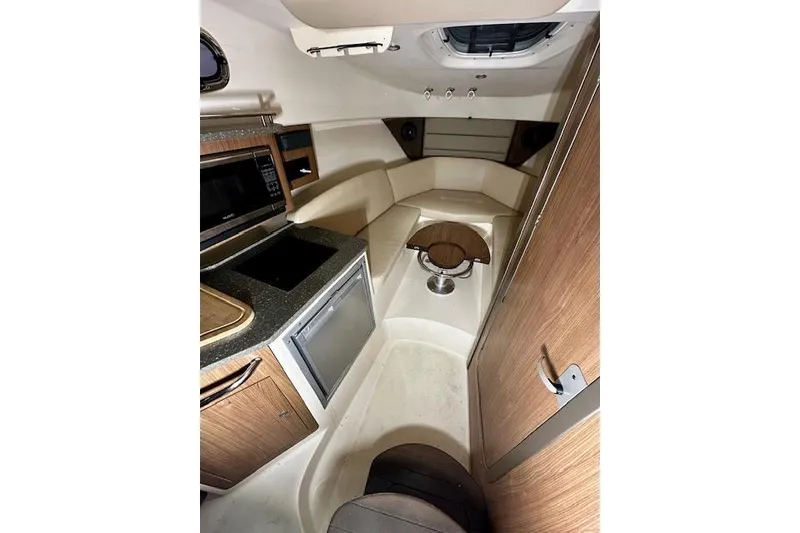 Slide: The Image of Interior of 2016 Boston Whaler 285 Conquest boat, featuring kitchenette and seating area. - 12