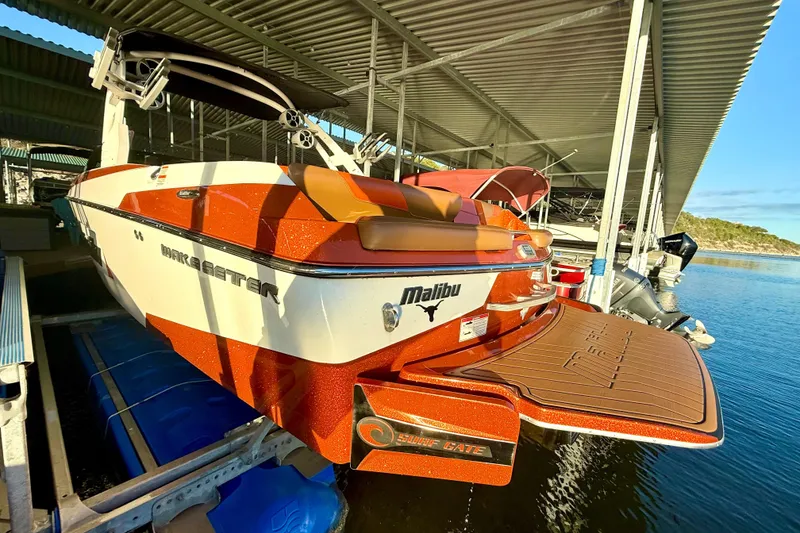 Slide: The Image of 2019 Malibu Wakesetter 23 LSV boat docked, featuring vibrant orange and white design. - 11
