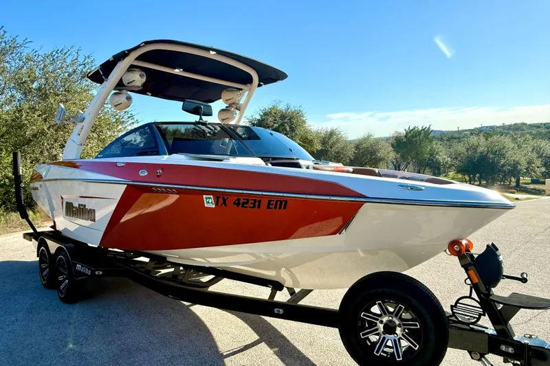 Slide: The Image of 2019 Malibu Wakesetter 23 LSV boat on trailer, red and white design, sunny day. - 25