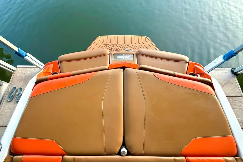 Slide: The Image of 2019 Malibu Wakesetter 23 LSV boat interior with tan and orange seating, docked by water. - 55