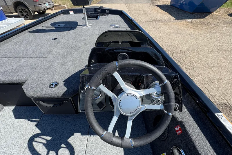 Slide: The Image of 2026 Lund 1875 Renegade boat interior with steering wheel and carpeted deck. - 16