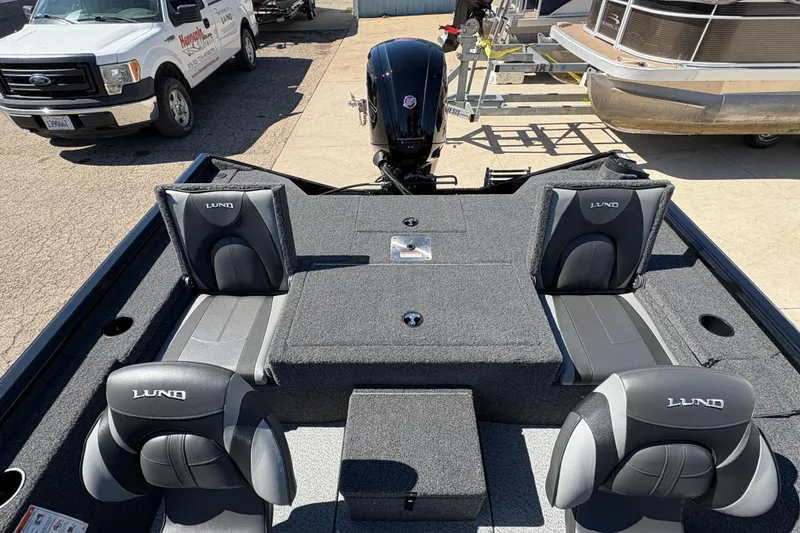 Slide: The Image of 2026 Lund 1875 Renegade boat interior with seating and motor, parked outdoors. - 18
