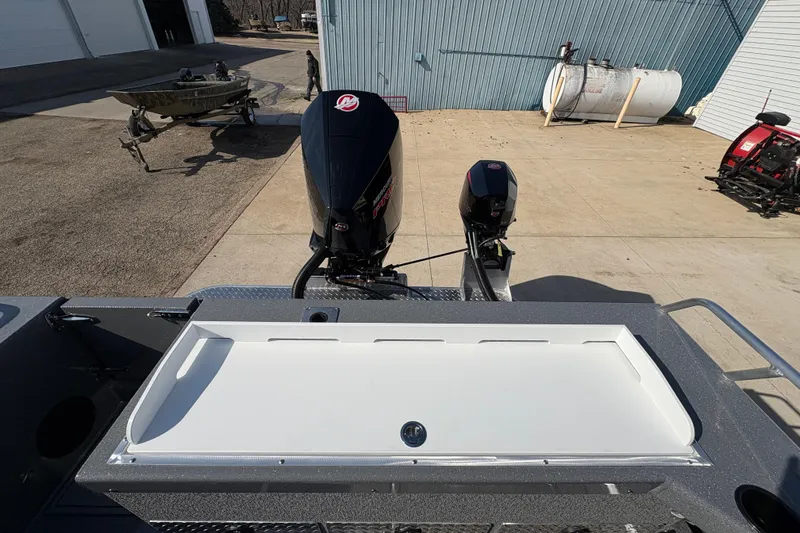 Slide: The Image of 2026 Lund 210 Heavy Gauge boat with dual outboard motors in a marina setting. - 48