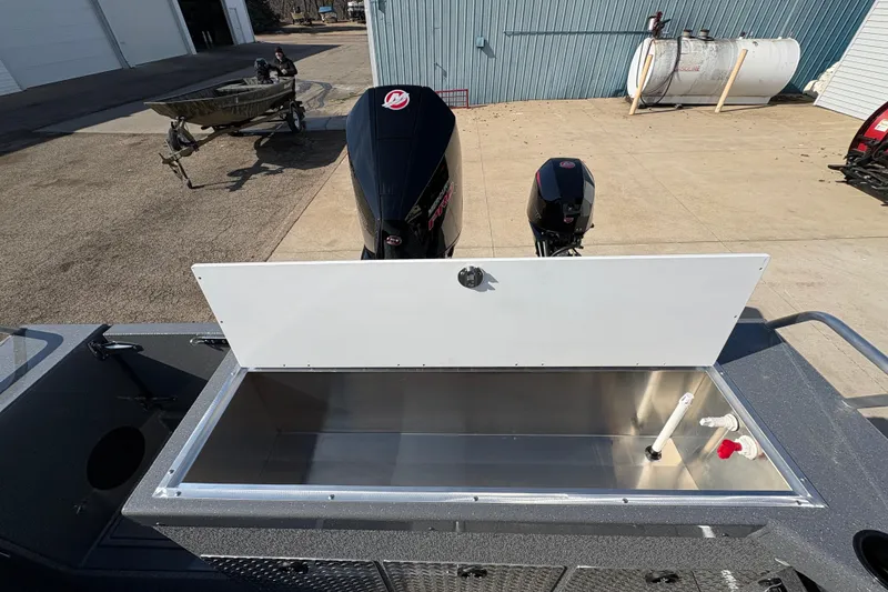 Slide: The Image of 2026 Lund 210 Heavy Gauge boat with open storage compartment and dual outboard motors. - 49