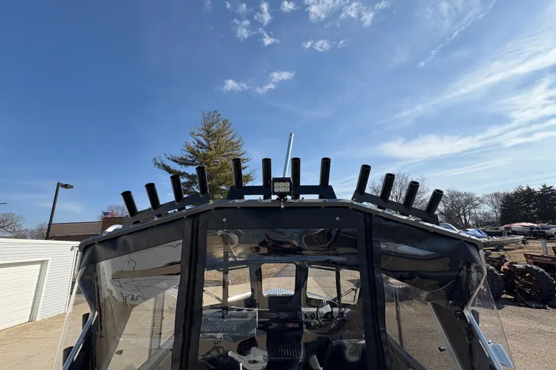 Slide: The Image of 2026 Lund 210 Heavy Gauge boat with rod holders under a clear blue sky. - 52