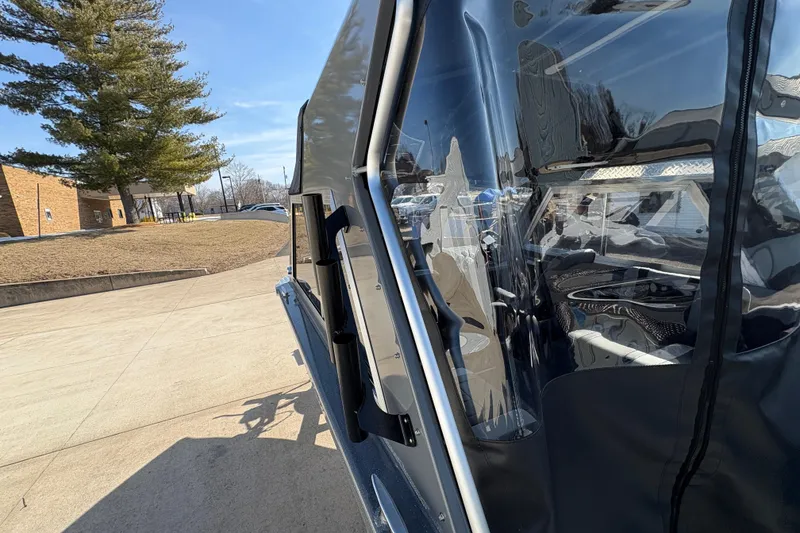 Slide: The Image of 2026 Lund 210 Heavy Gauge boat with clear canopy, parked outdoors. - 53