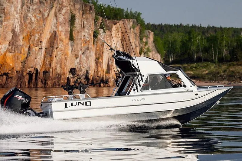Slide: The Image of Manufacturer Provided Image: 2025 Lund 210 Heavy Gauge boat cruising on a scenic lake with rocky cliffs. - 54