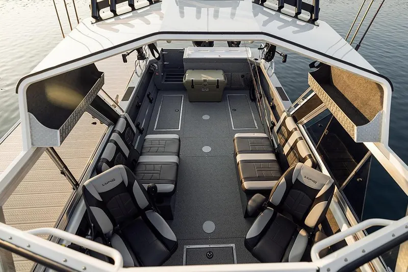 Slide: The Image of Manufacturer Provided Image: 2025 Lund 210 Heavy Gauge boat interior with seating and storage, docked on calm water. - 58