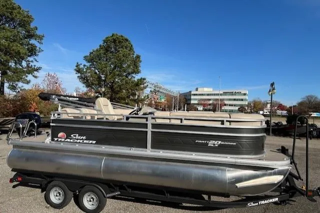 Slide: The Image of 2025 Sun Tracker Party Barge 20 DLX pontoon boat on trailer, outdoor setting. - 2