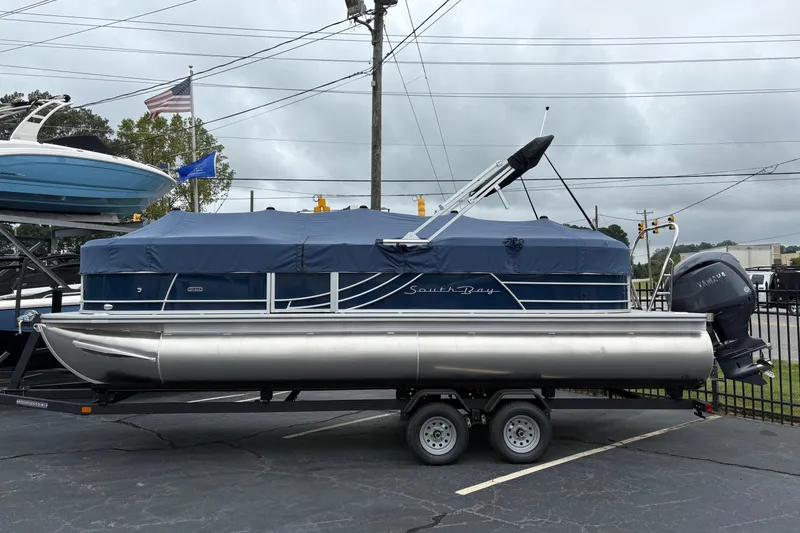 The Image of 2026 South Bay S 224 pontoon boat with blue cover on trailer. - 0