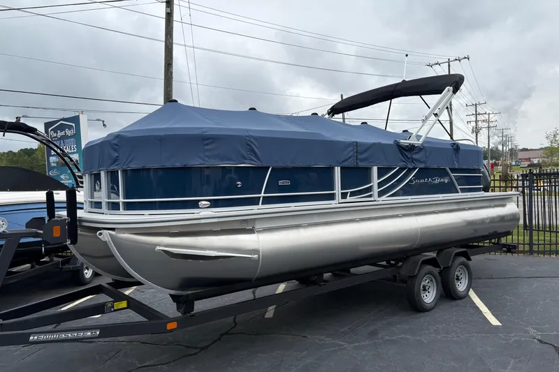 Slide: The Image of 2026 South Bay S 224 pontoon boat with blue cover on a trailer. - 2