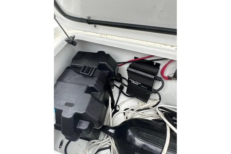 Slide: The Image of 2024 Sea Hunt Gamefish 25 battery compartment with charger and cables. - 10