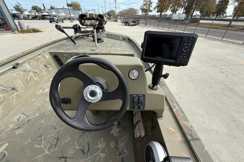 Slide: The Image of 2025 Tracker Grizzly 1754 SC boat interior with steering wheel and Garmin display. - 13