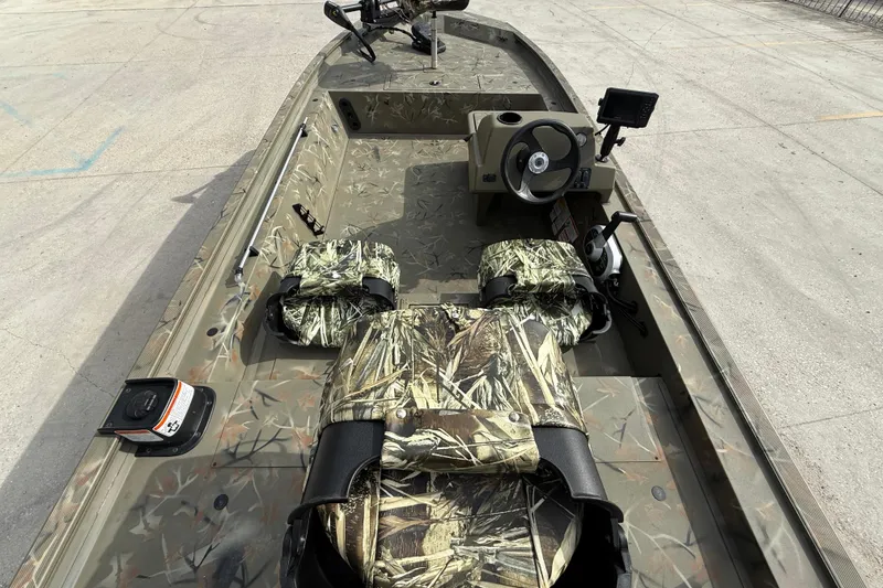 Slide: The Image of 2025 Tracker Grizzly 1754 SC boat interior with camouflage seating and steering console. - 8