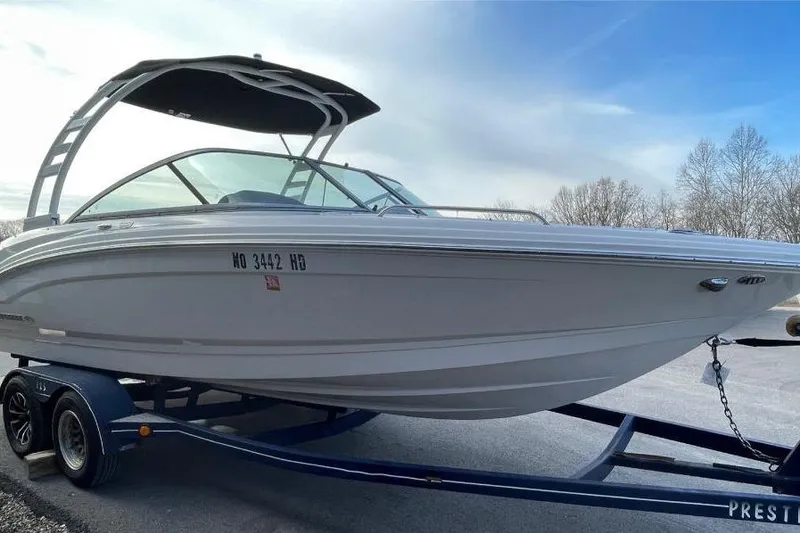 Slide: The Image of 2023 Chaparral 23 SSi boat on trailer, sleek design, blue sky background. - 2