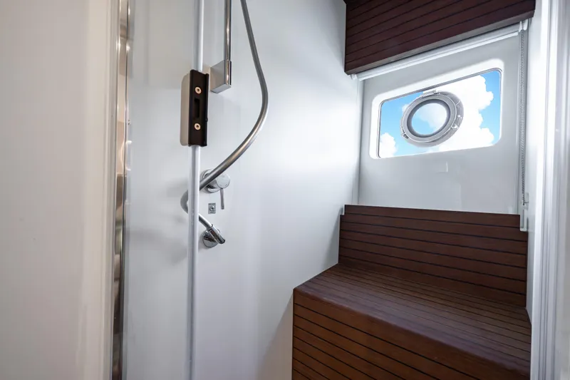 Slide: The Image of Luxurious shower area on 2024 Azimut Fly 68 yacht with wooden accents and porthole window. - 24