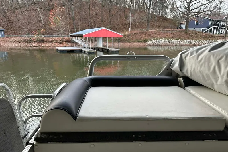 Slide: The Image of 2015 PlayCraft 25 Clipper boat with cushioned seating, docked near a serene lakeside. - 10