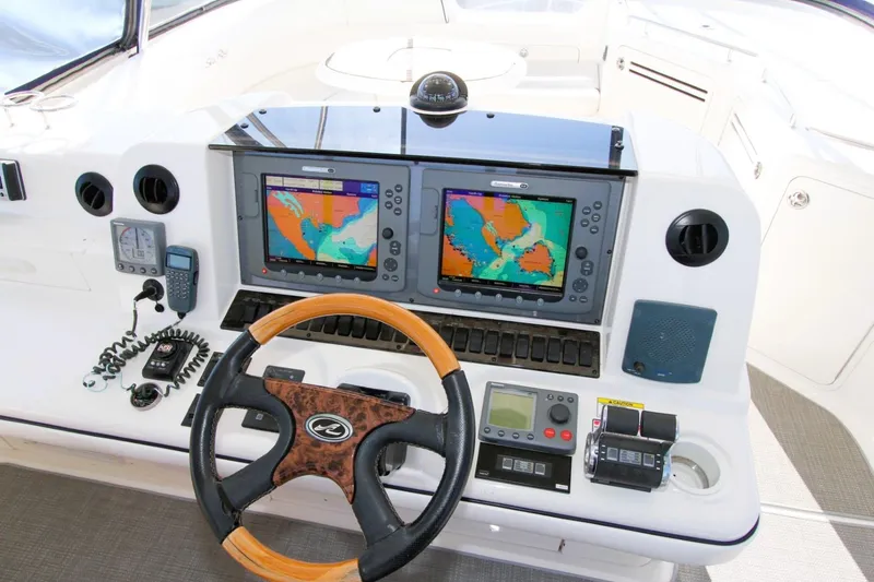 Slide: The Image of 2007 Sea Ray 580 Sedan Bridge helm with dual navigation screens and wooden steering wheel. - 31
