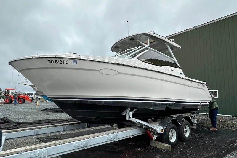 Slide: The Image of 2022 Cutwater C-24 DC boat on trailer, parked outdoors near a green building. - 3