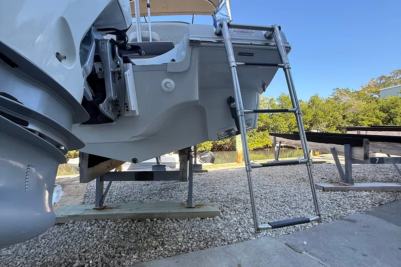 Slide: The Image of 2022 Crownline Eclipse E235 XS boat with ladder on gravel surface. - 12