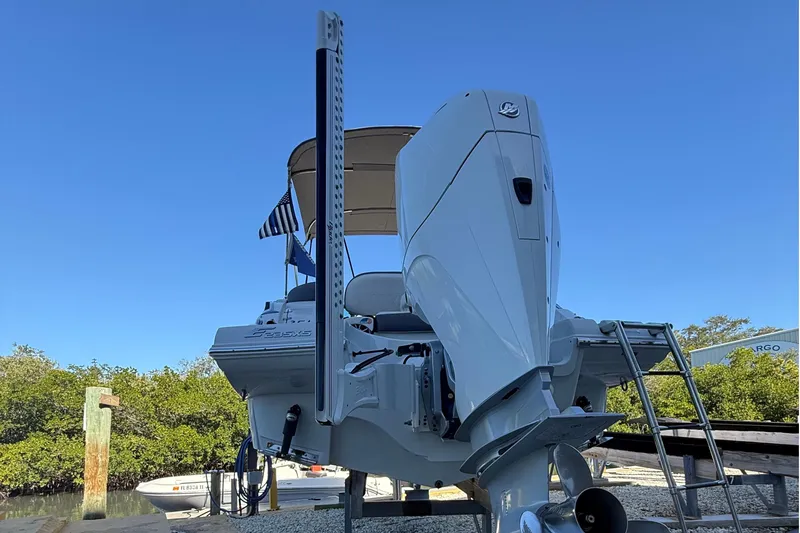 Slide: The Image of 2022 Crownline Eclipse E235 XS boat with outboard motor and ladder, docked under clear sky. - 14