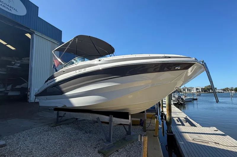 Slide: The Image of 2022 Crownline Eclipse E235 XS boat docked at a marina under clear blue skies. - 2